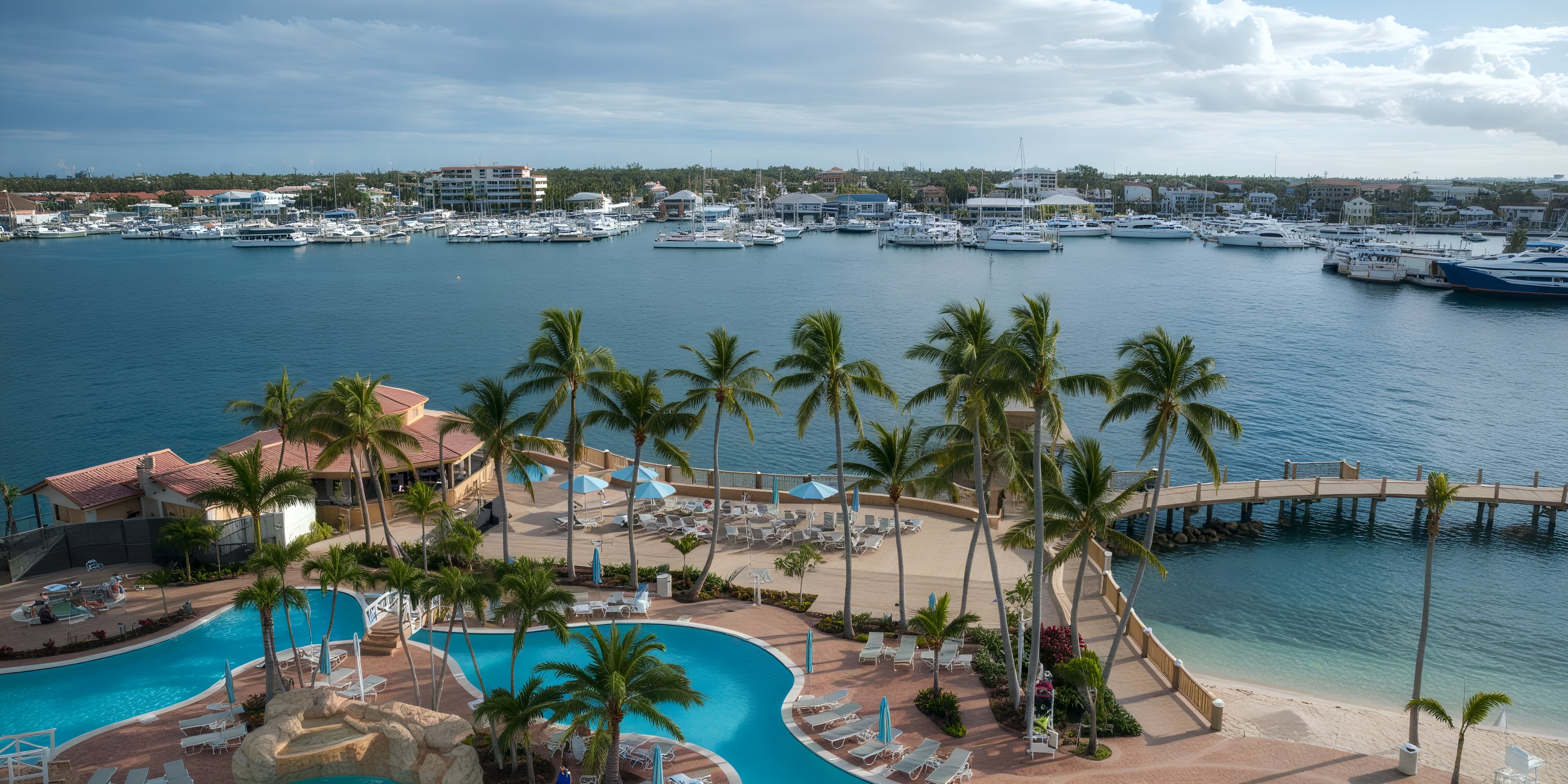 Warwick Paradise Island Bahamas: a dreamy destination wedding spot with resort pools, palms, yachts, and clouds.