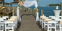 Destination wedding dock setup at Warwick Paradise Island Bahamas, featuring decorated chairs and arch.