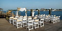 White chairs arranged for a destination wedding face a floral arch on the dock at Warwick Paradise Island.