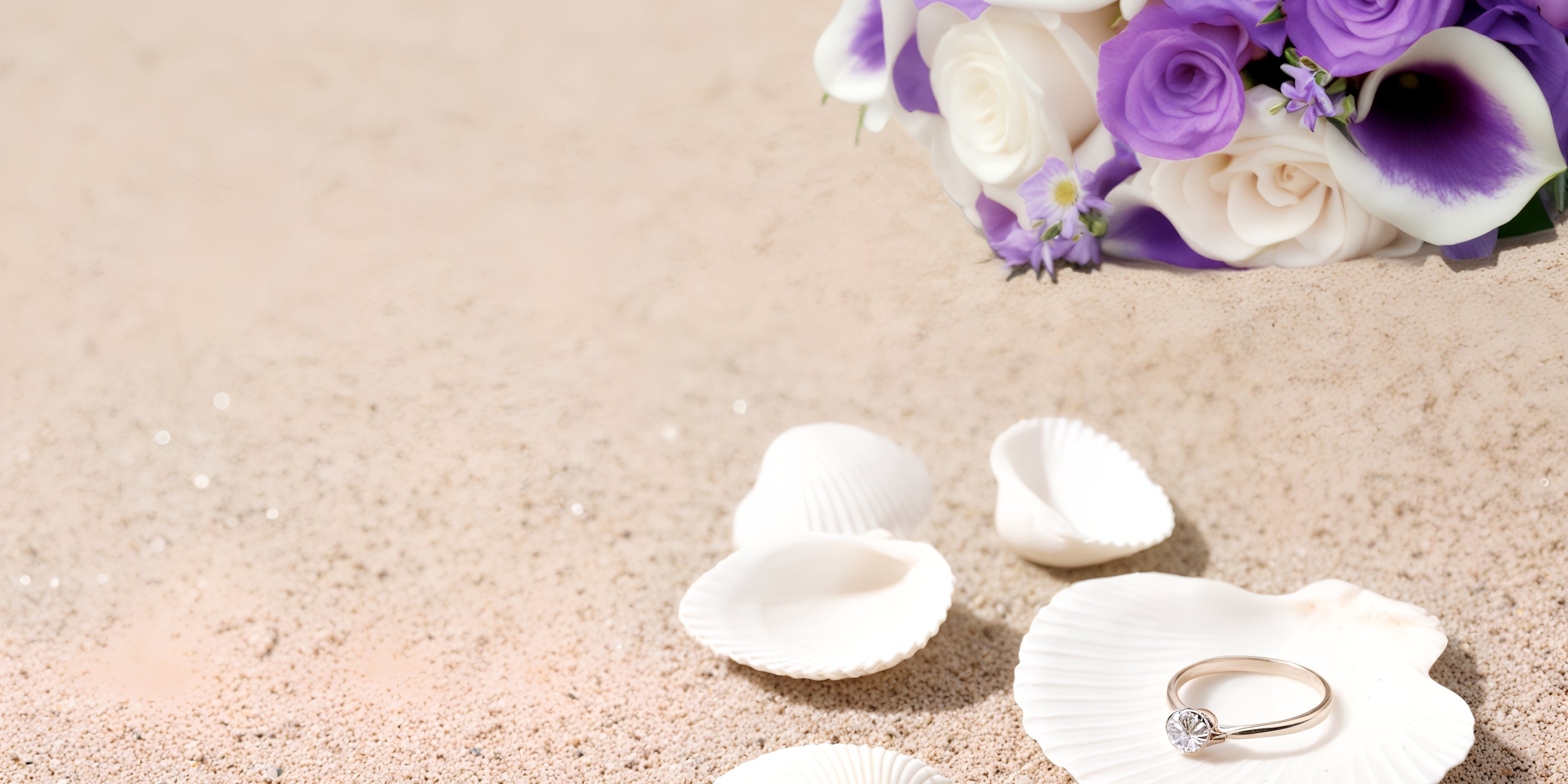 Wedding ring at Warwick Paradise Island Bahamas on seashells, white and purple flowers atop sand.
