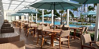 Wicker tables and chairs set for a destination wedding under umbrellas by the pool at Warwick Paradise Island.