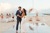 Shirley and William share a dance on a mirrored floor at their destination wedding as guests watch.