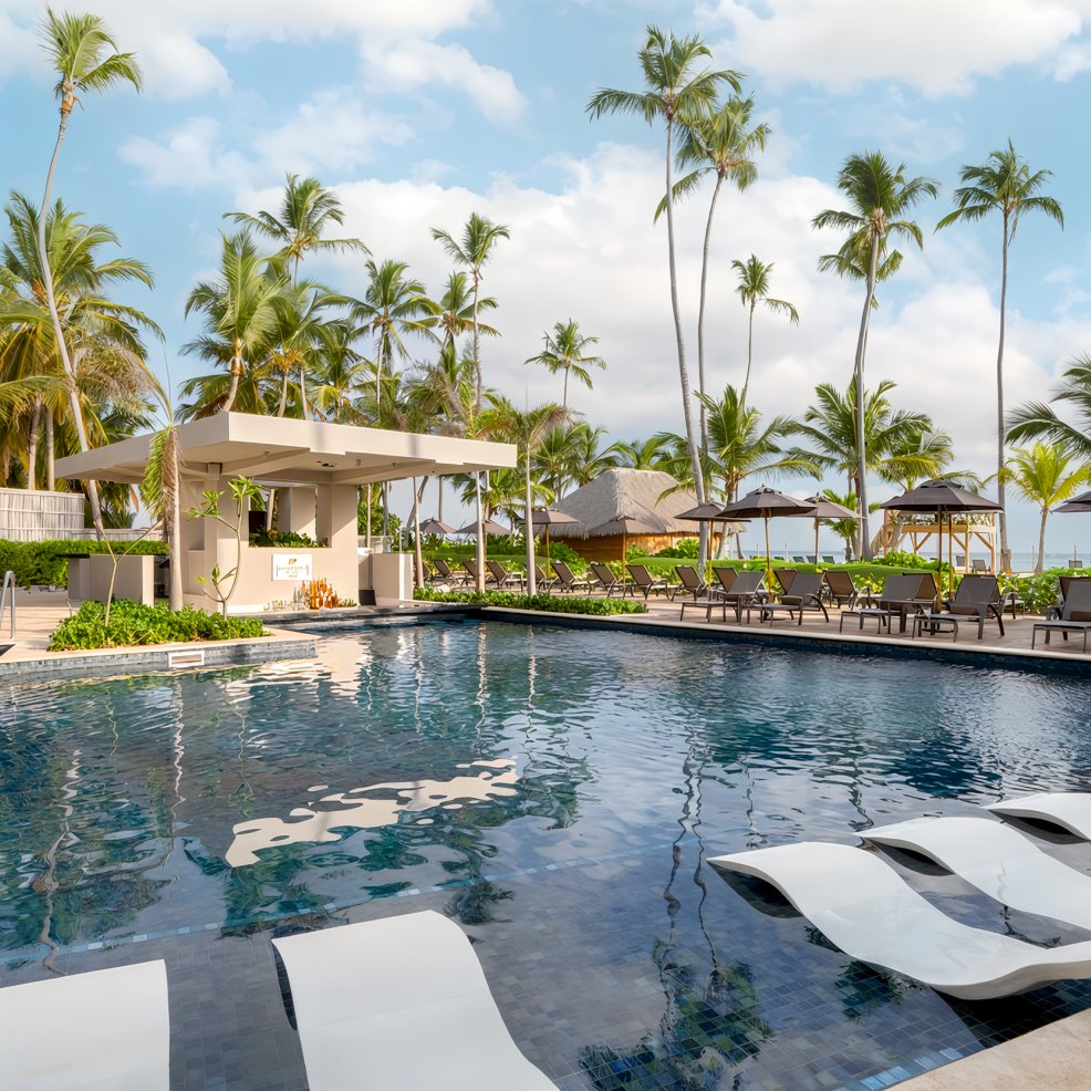Outdoor pool with lounge chairs, palm trees, and cabanas—ideal for a destination wedding celebration.