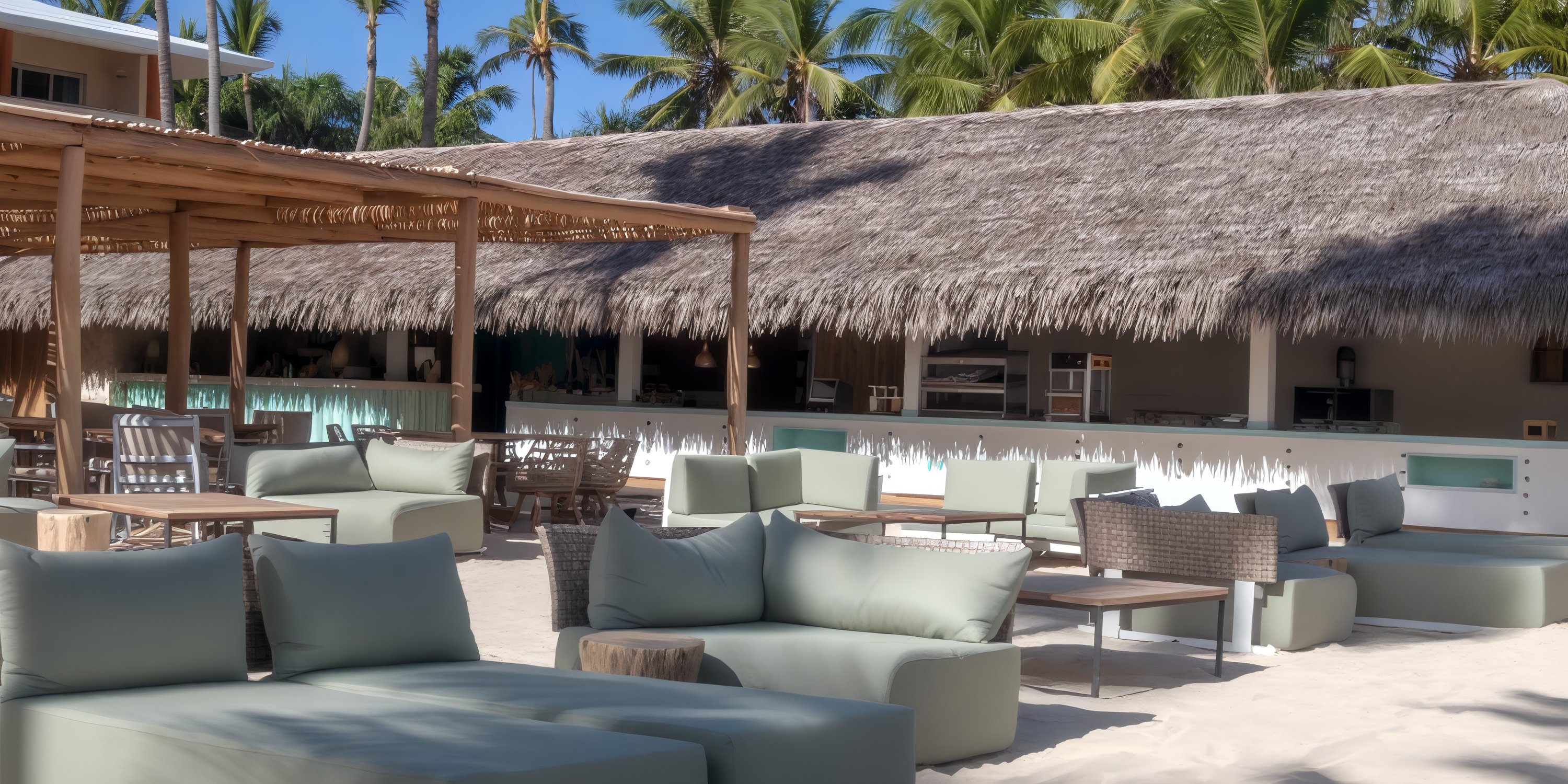 Outdoor beach bar with cushioned seating and wooden tables, perfect for a destination wedding setting.
