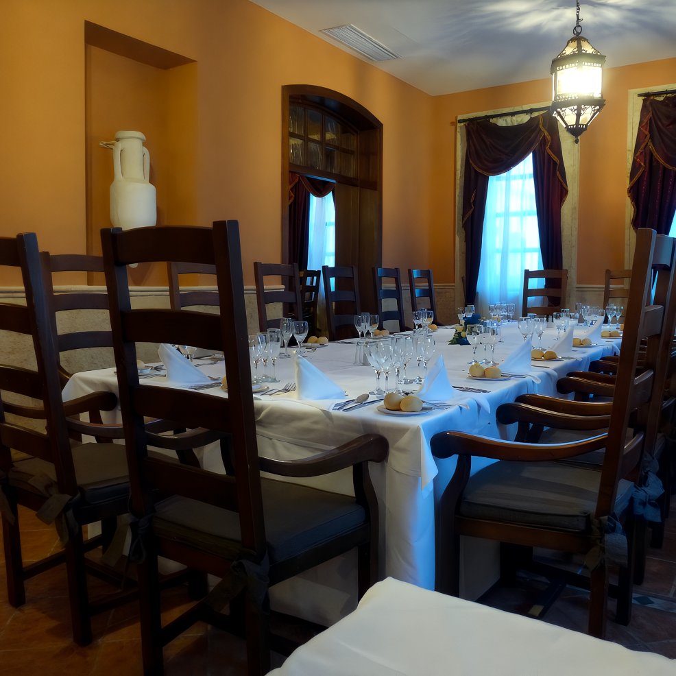 Elegant dining room with a long table set for a destination wedding, surrounded by wooden chairs.