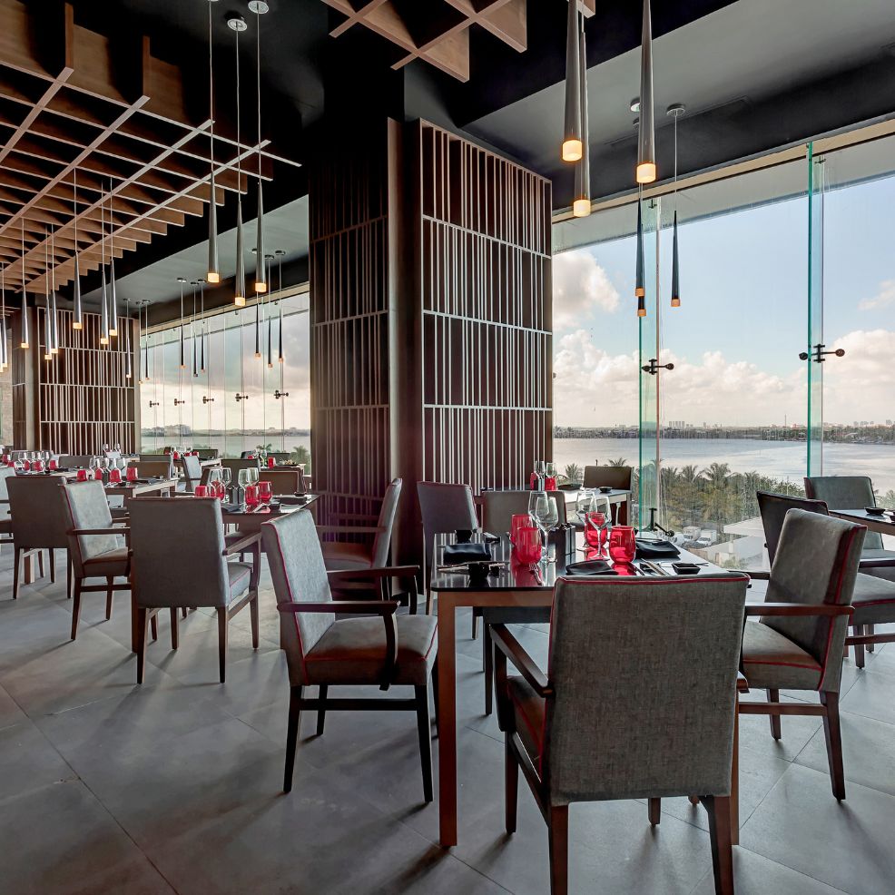 Elegant restaurant interior with set tables, large windows, and a waterfront view ideal for weddings.