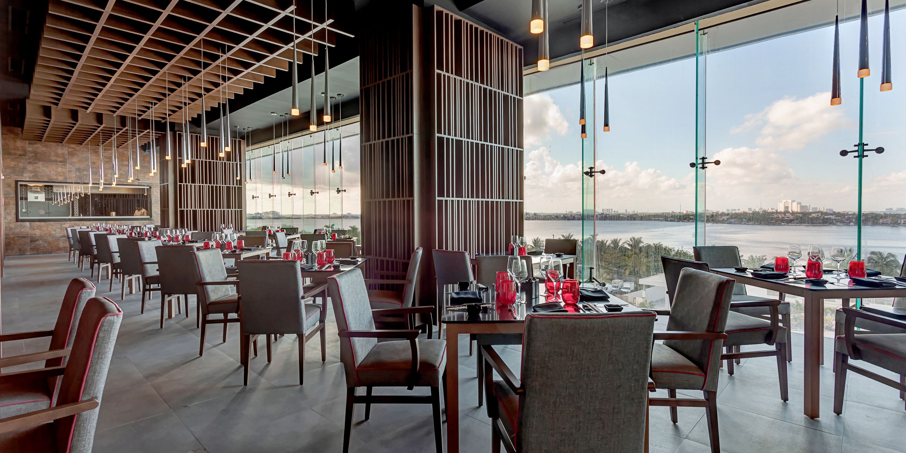 Chic restaurant set for a wedding, featuring floor-to-ceiling windows and stunning waterfront views.