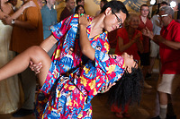 Brianna and Aszah dance together in matching floral outfits at a festive destination wedding indoors.