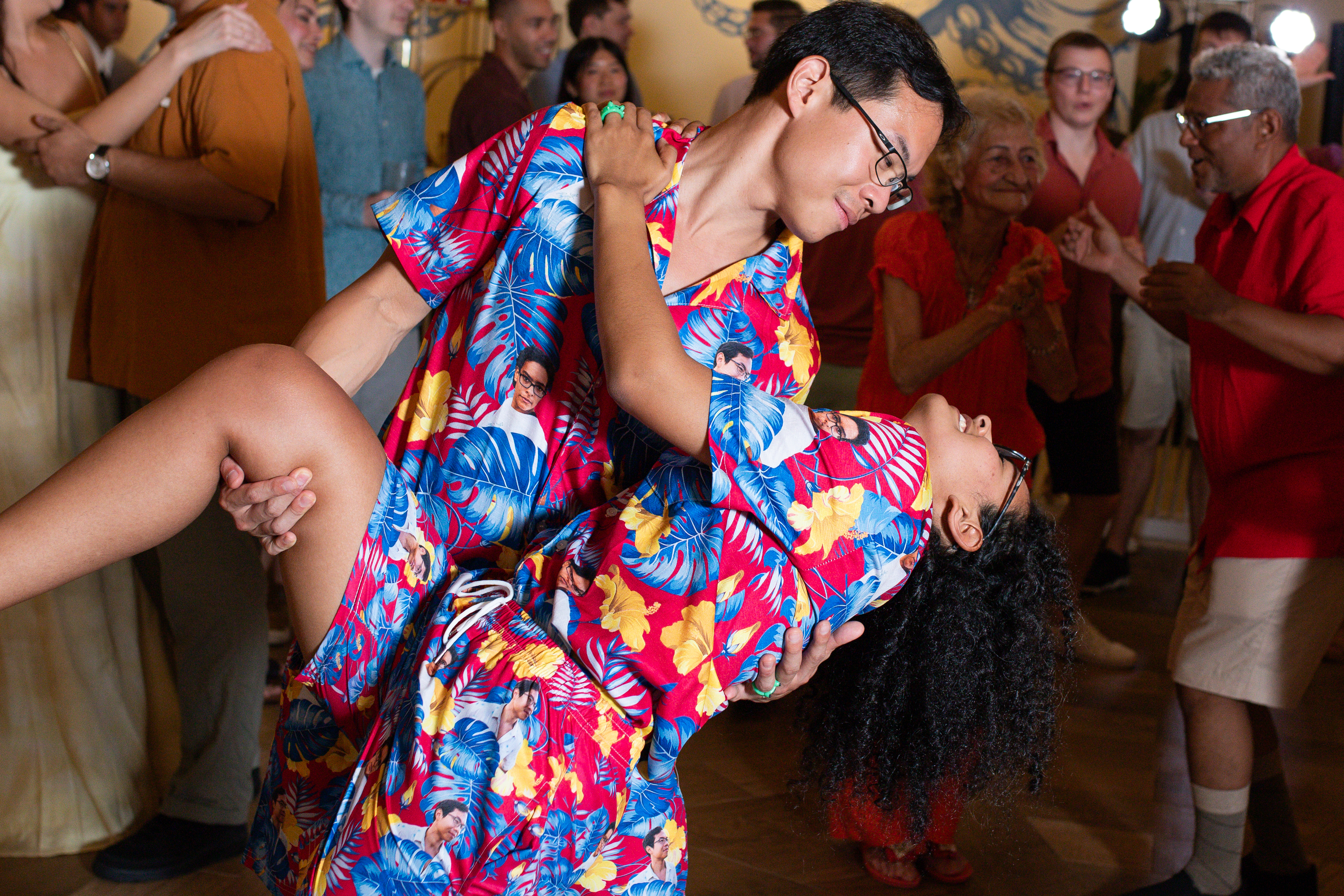 Brianna and Aszah dance together in matching floral outfits at a festive destination wedding indoors.