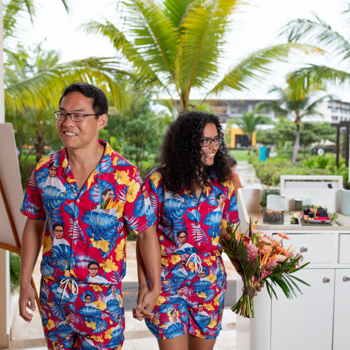 Couple in matching Brianna and Aszah outfits, holding hands at a destination wedding with a bouquet.