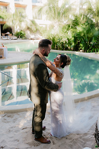Shirley and William embrace by a poolside on a sunny day, celebrating their destination wedding.