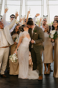Shirley and William kiss at their destination wedding as the party in gold attire pops champagne.