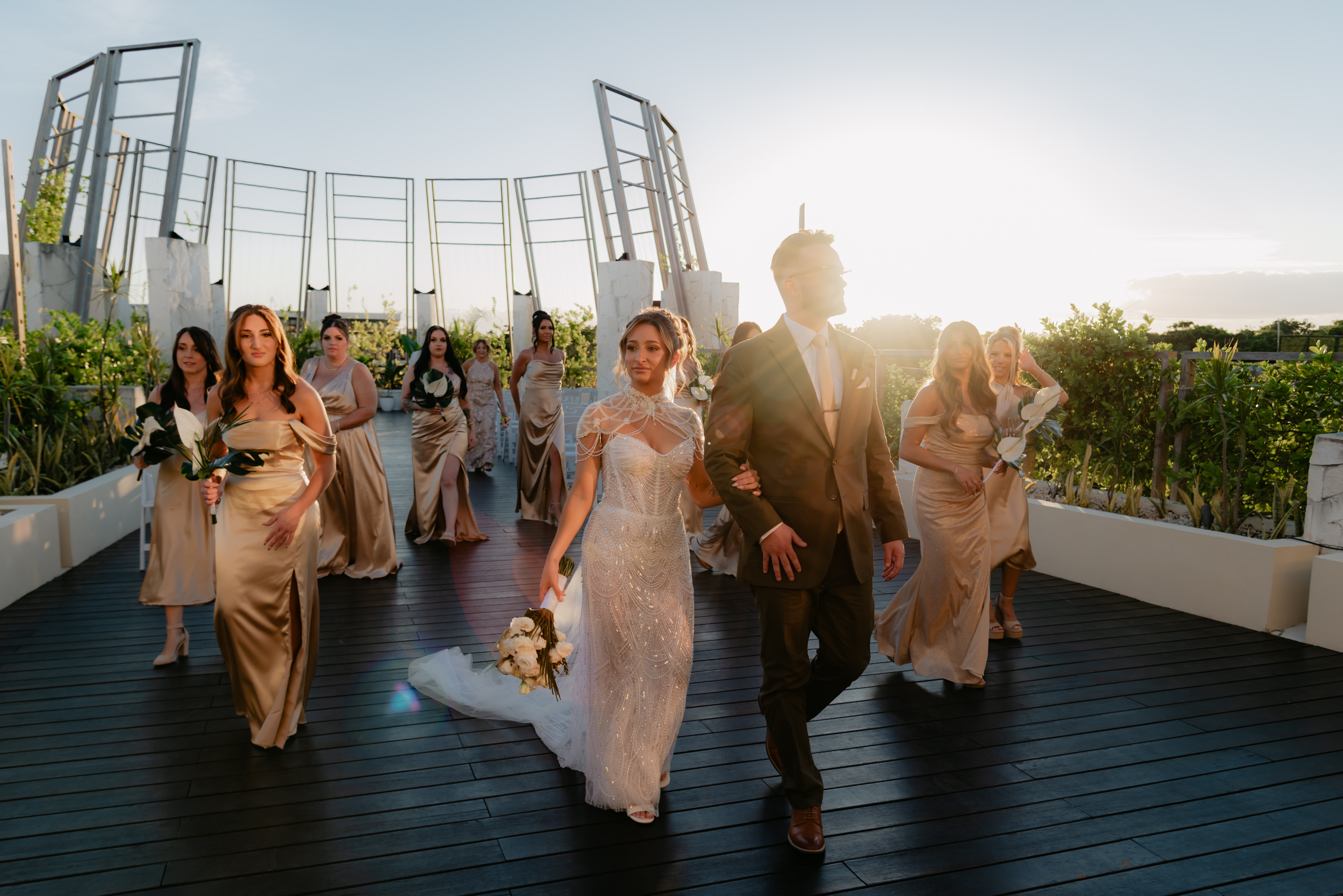 Shirley and William's destination wedding: bride, groom, and bridesmaids in gold at sunset outdoors.