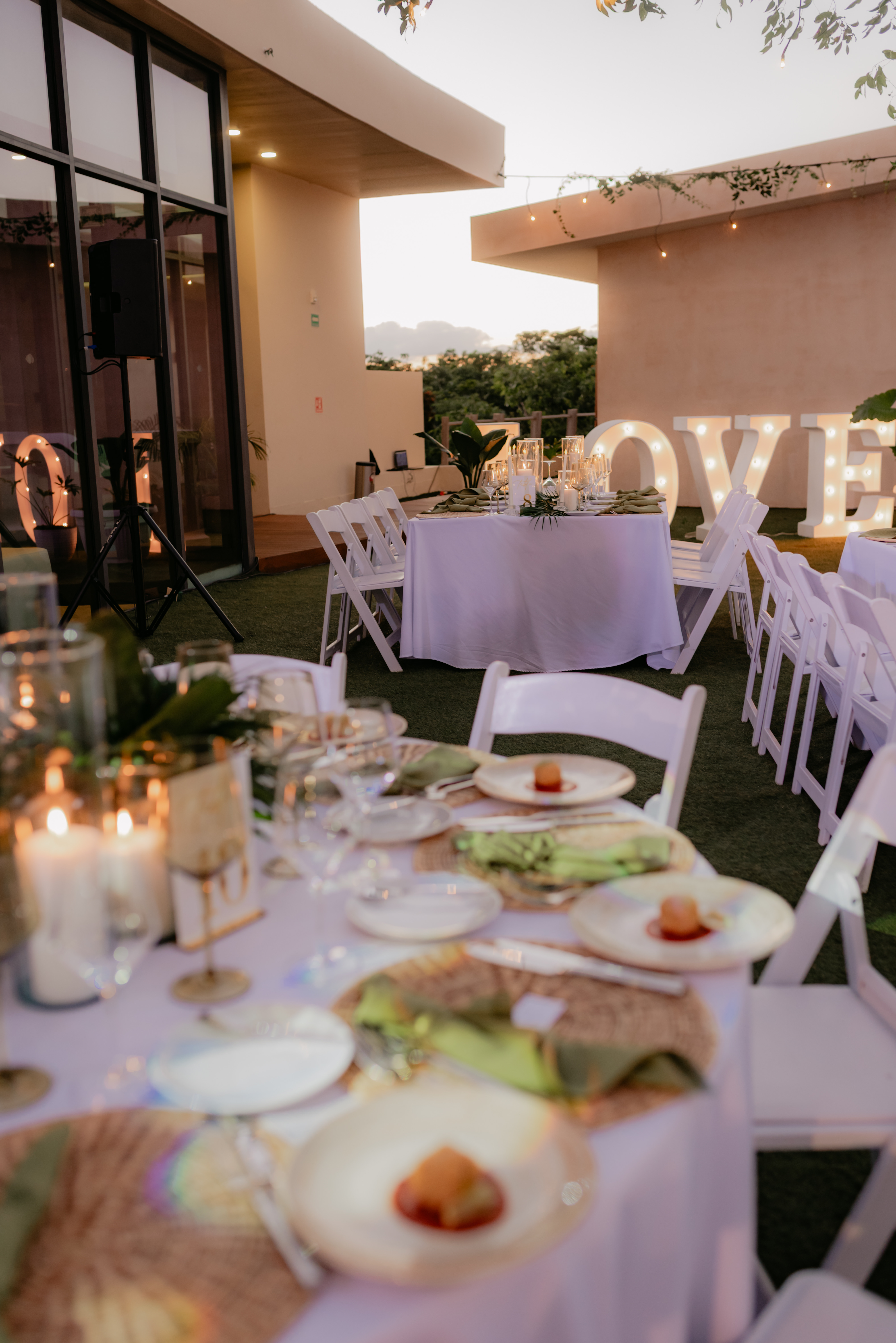 Wedding table setup for Shirley and William with white chairs, plates, candles, and a "LOVE" sign.