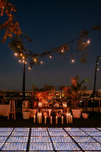 Shirley and William destination wedding on a rooftop with string lights, candles, plants, and glowing floor.