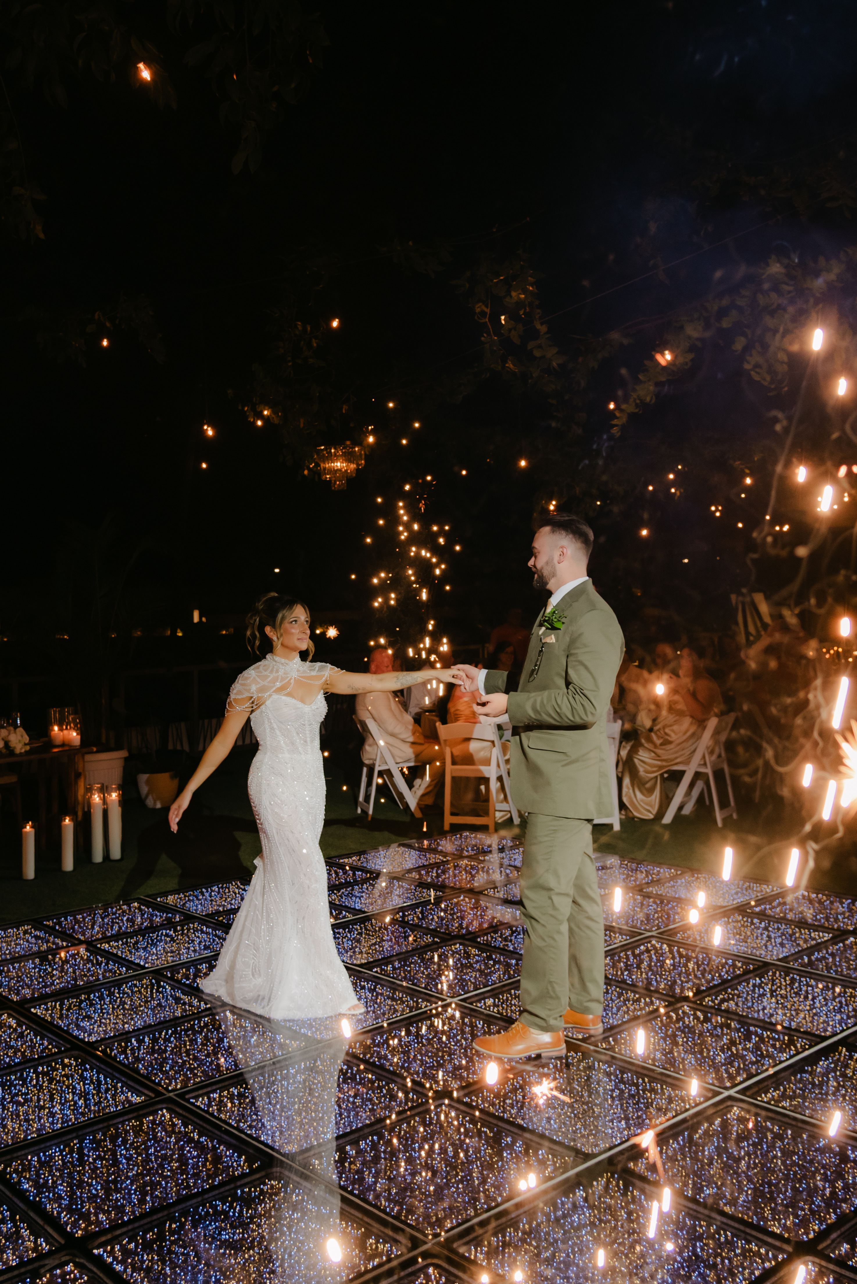 Shirley and William share a dance at their destination wedding on a lit, reflective floor at night.