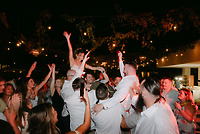 Shirley and William are lifted by guests during a festive nighttime destination wedding celebration.