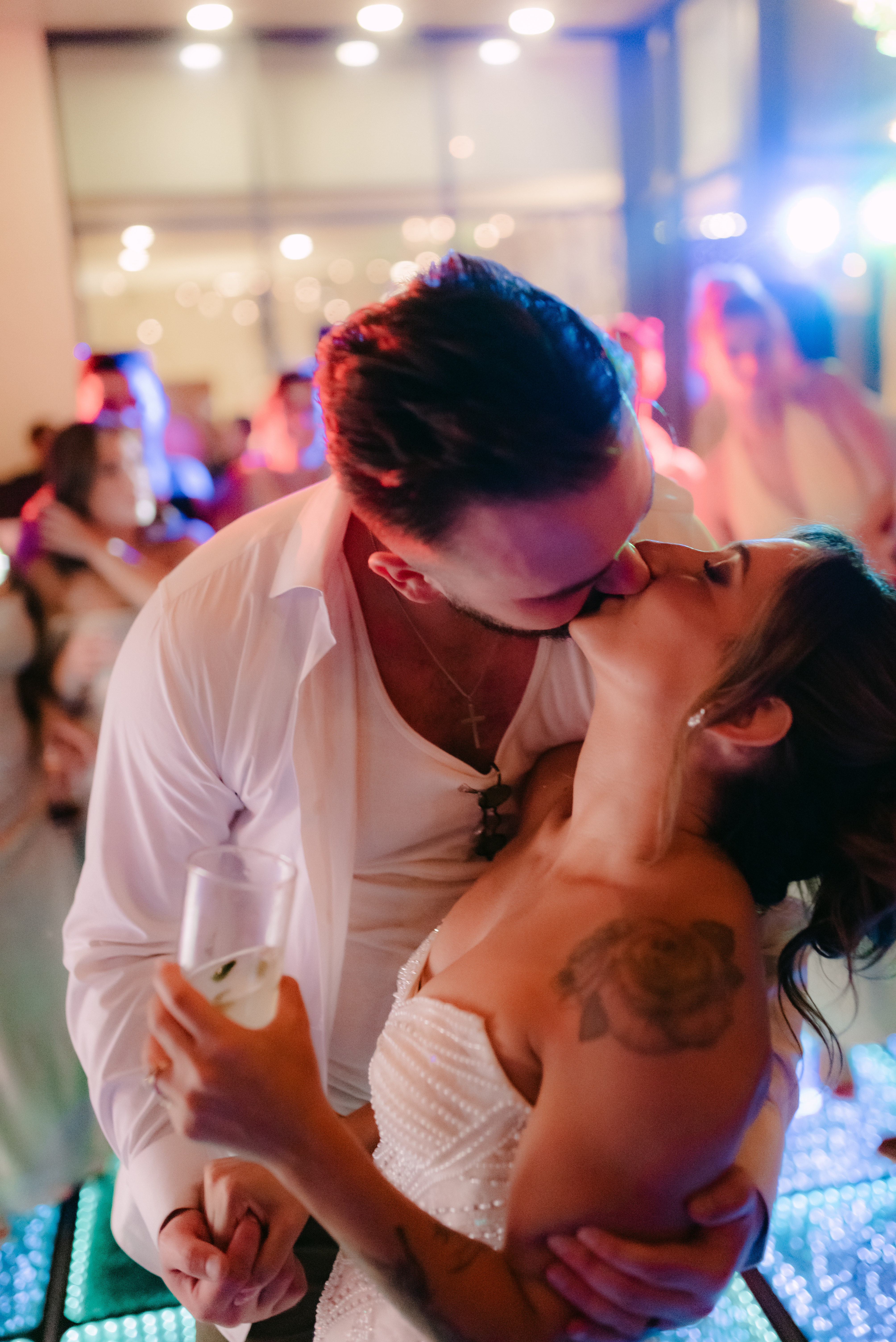 Shirley and William share a kiss on the dance floor at a destination wedding; she holds a drink in white.
