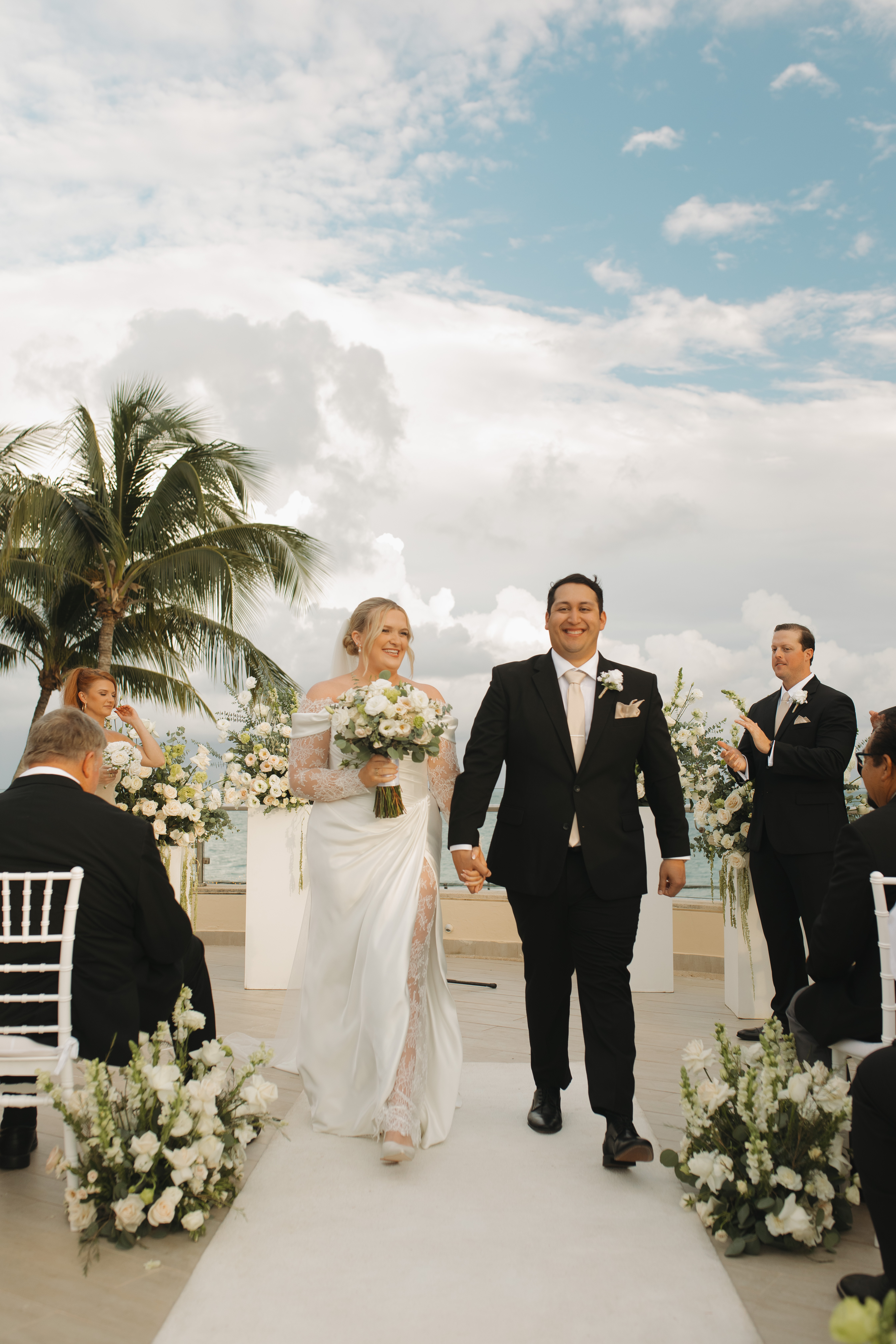Madison and Robert walk hand in hand down the aisle at their outdoor destination wedding ceremony.