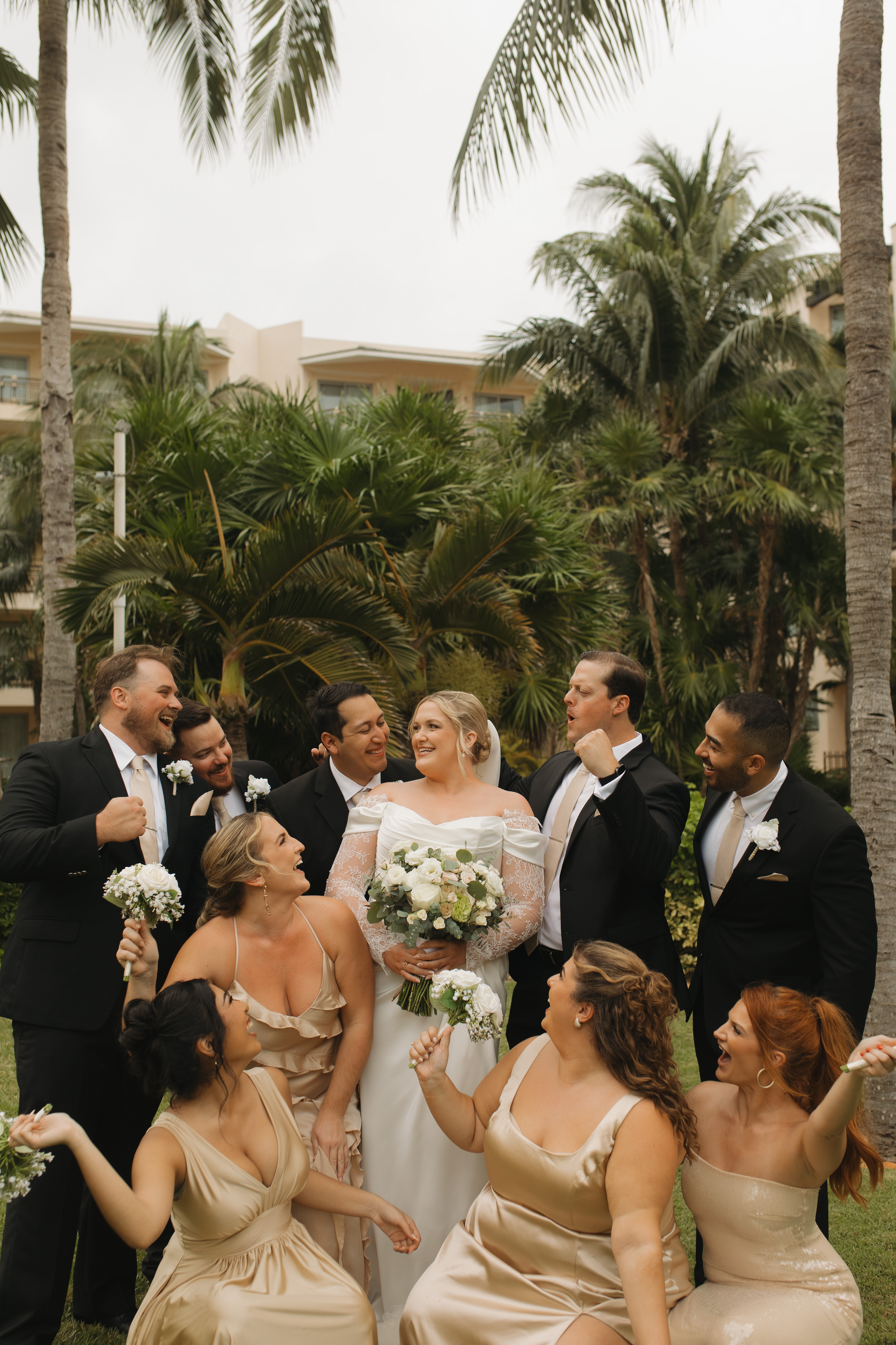 Madison and Robert celebrate their destination wedding outdoors with their party beneath palm trees.