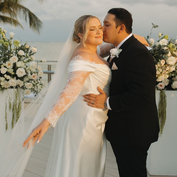 Madison and Robert pose in a loving embrace, surrounded by flowers at their destination wedding outdoors.