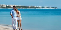 A couple strolls the beach at Ocean Coral and Turquesa, a dreamy destination wedding spot by clear water.