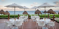 Ocean Coral and Turquesa's patio, ideal for a destination wedding, has white tables, umbrellas, and ocean views.