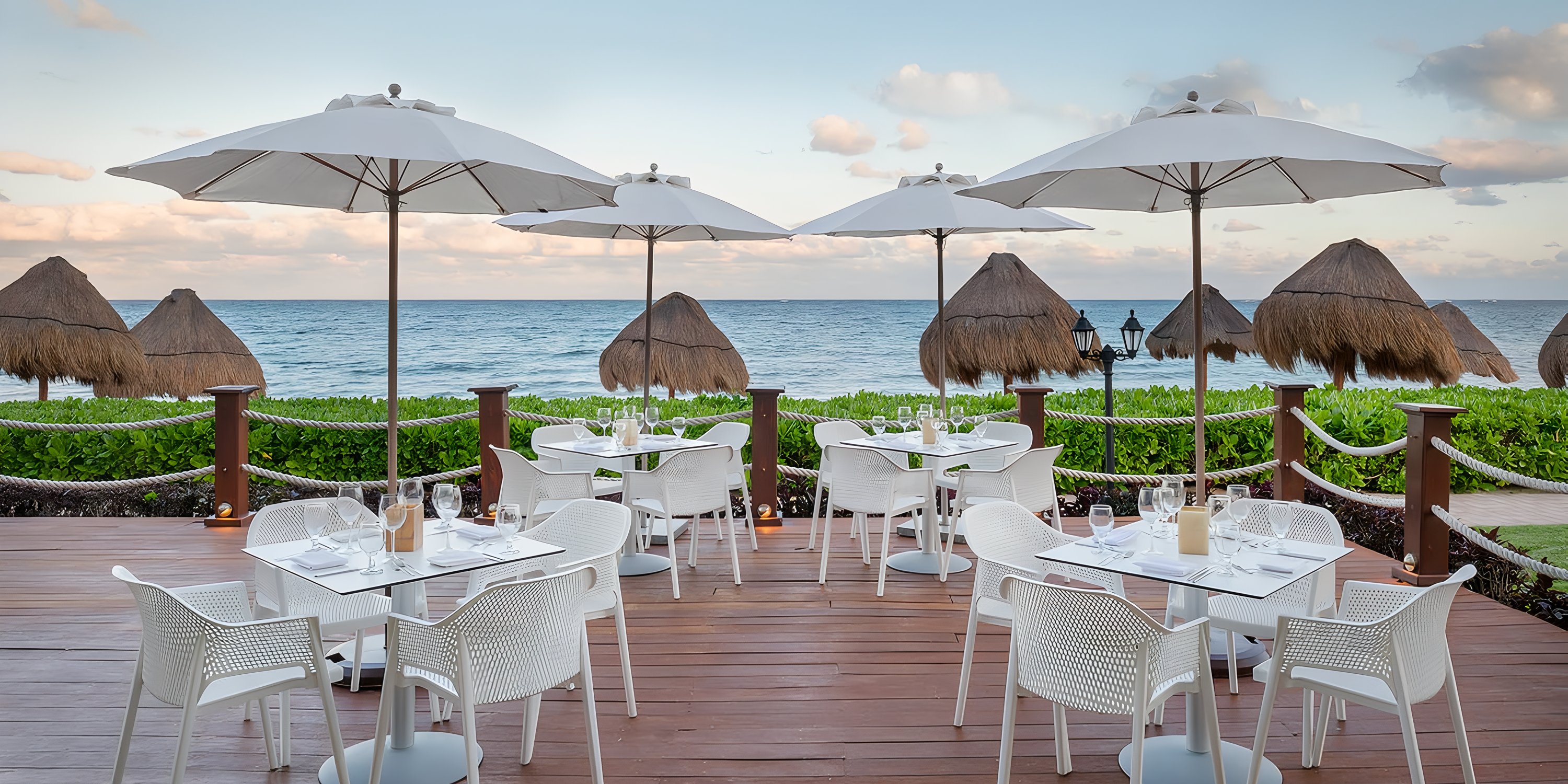 Ocean Coral and Turquesa's patio, ideal for a destination wedding, has white tables, umbrellas, and ocean views.