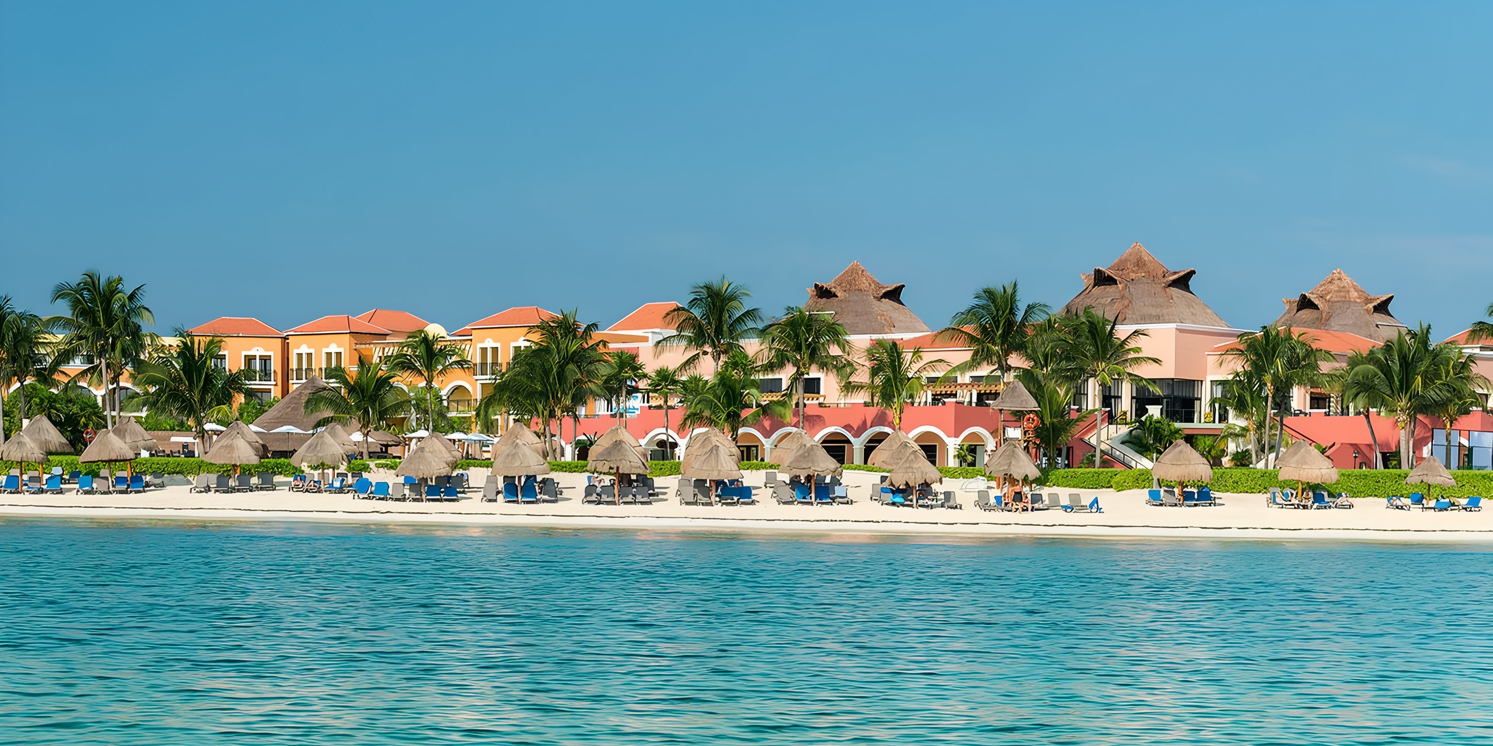 Ocean Coral and Turquesa: a stunning destination wedding resort with loungers by turquoise water.