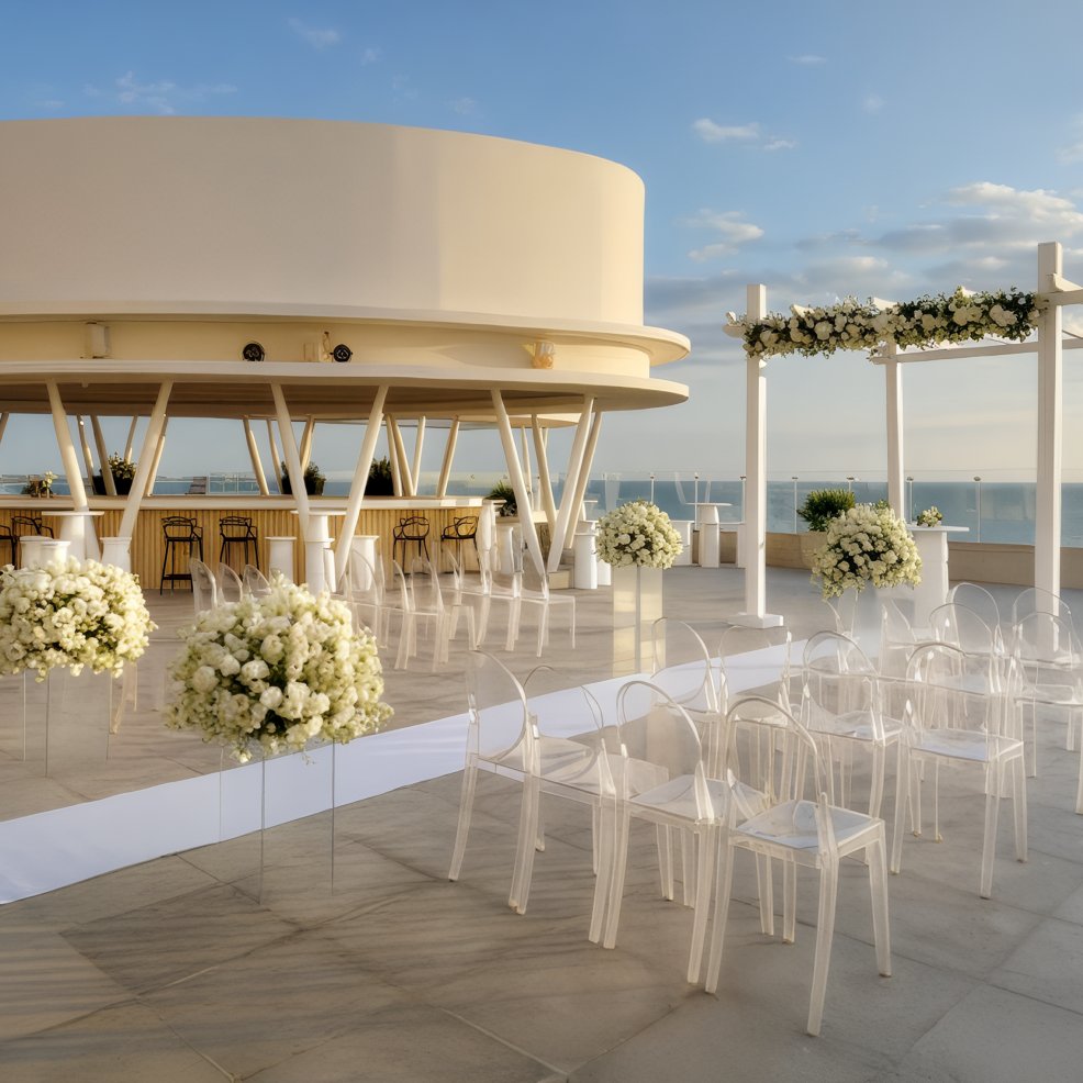 Rooftop destination wedding setup with clear chairs, elegant florals, and a stunning ocean backdrop.
