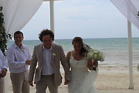Stephanie and Connor hold hands on the beach following their romantic destination wedding ceremony.