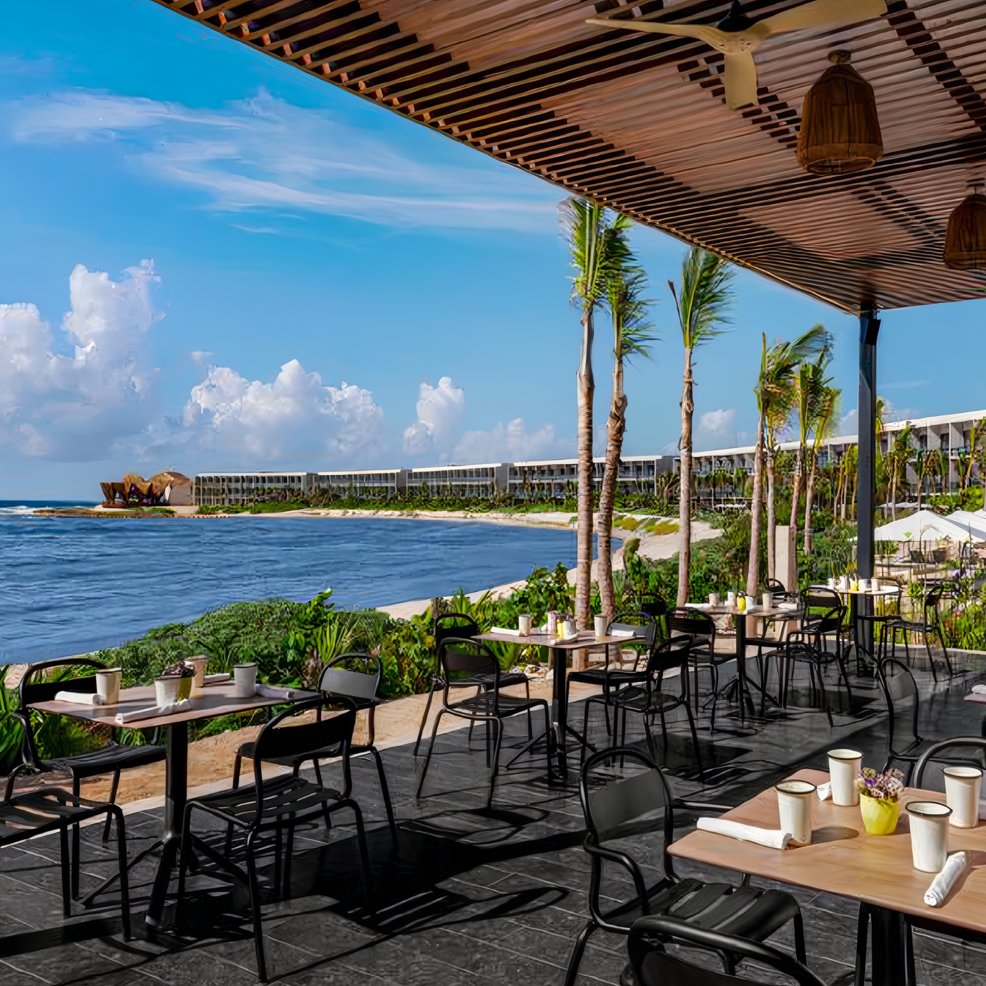 Outdoor restaurant patio with tables and chairs, perfect for a destination wedding, overlooks the ocean.