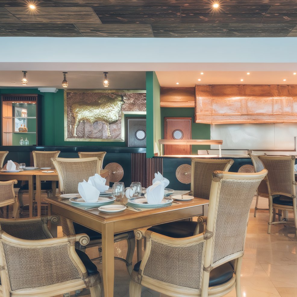 Elegant restaurant interior, ideal for a destination wedding, with set tables, wicker chairs, and wall art.