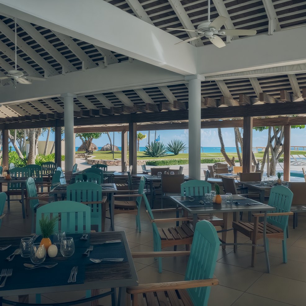 Open-air restaurant with teal chairs, perfect for a destination wedding, overlooks pool and ocean views.