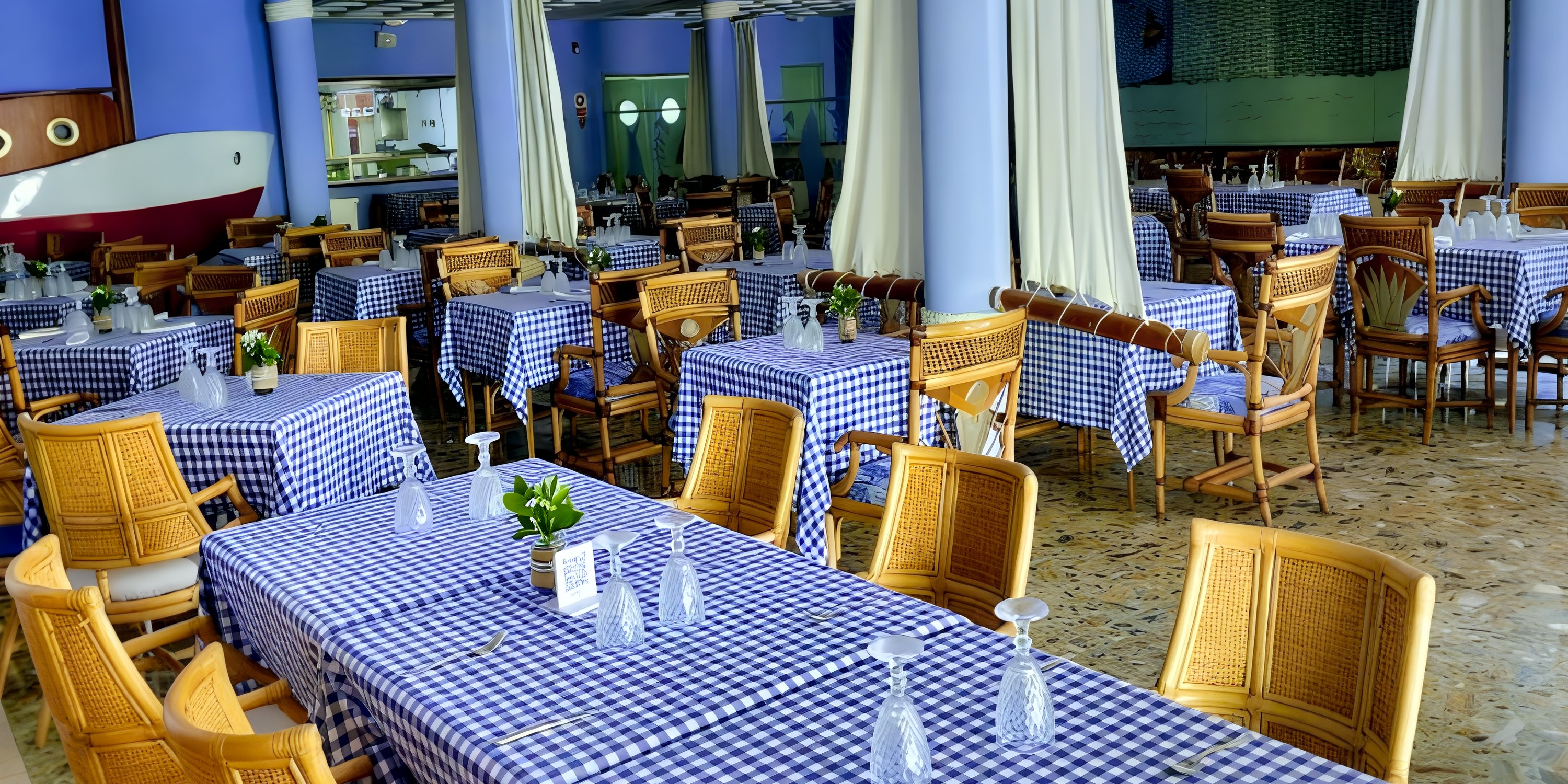 Dining area styled for a destination wedding, featuring blue checkered tablecloths and wicker chairs.