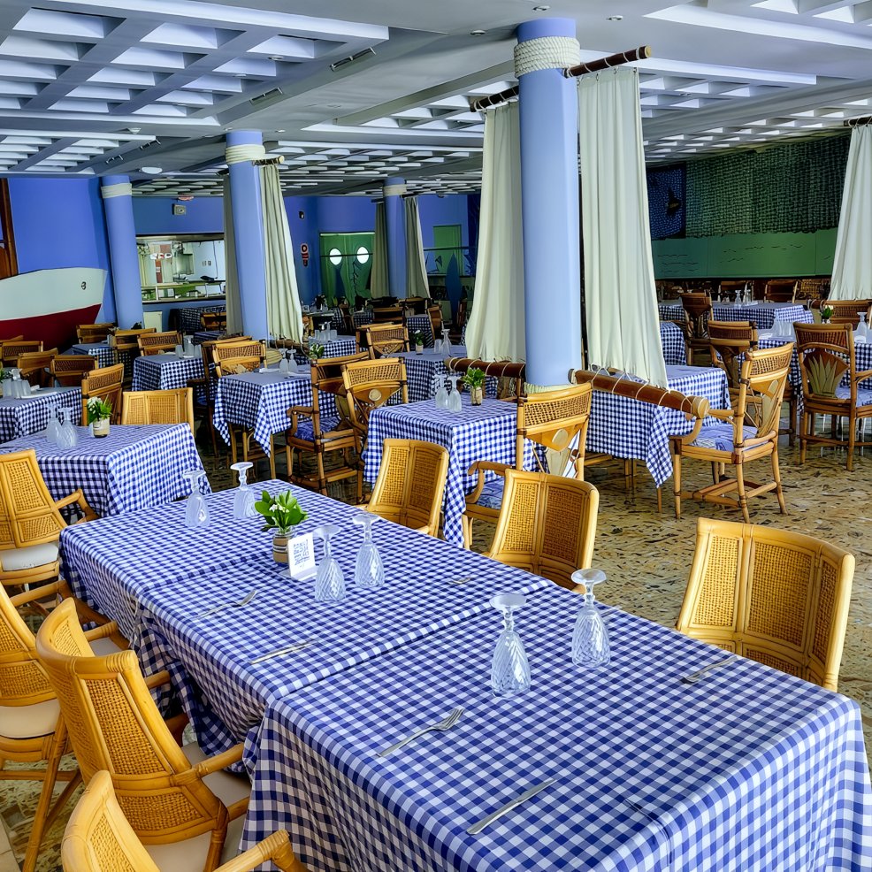 Restaurant dining area with blue checkered tablecloths and wooden chairs, set up for a destination wedding.