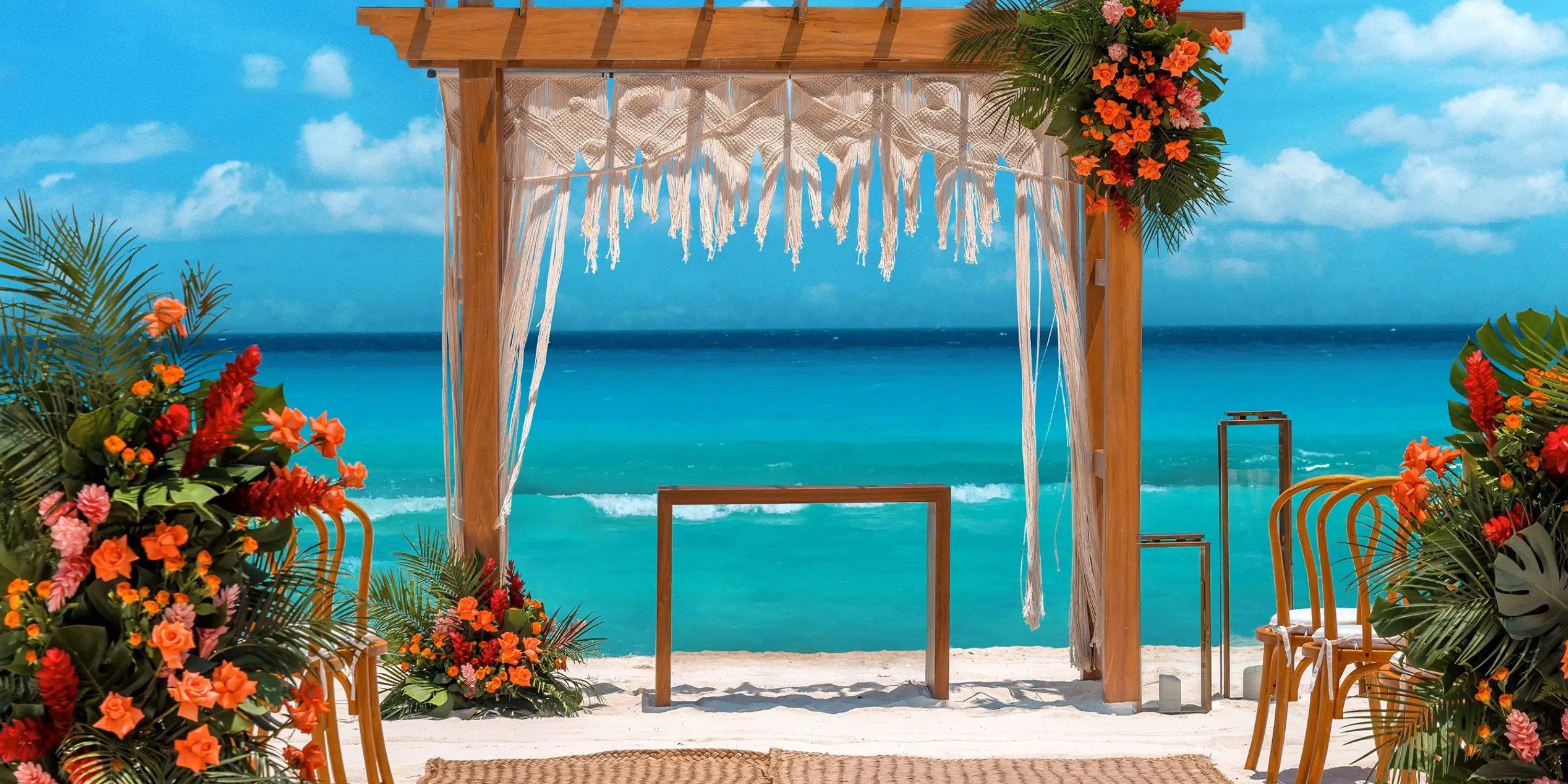 Wedding arch adorned with flowers on the beach at Moon Palace The Grand Punta Cana, perfect for a destination wedding by turquoise sea.