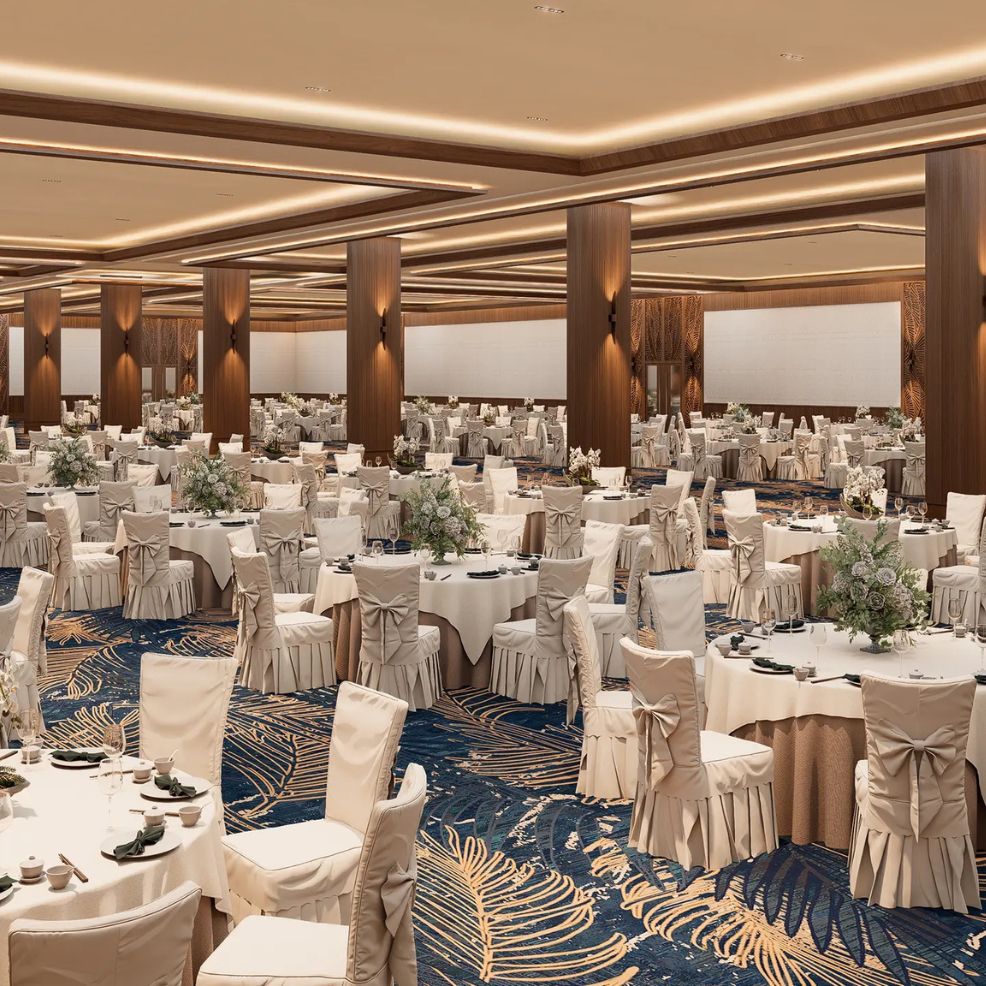 Spacious banquet hall with round tables, white chairs, and floral centerpieces for a destination wedding.