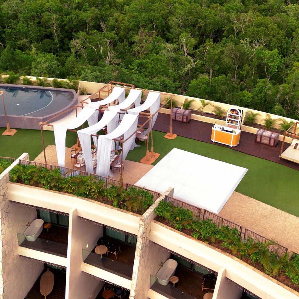 Destination wedding venue featuring draped canopies, pool, bar area, and forest backdrop.