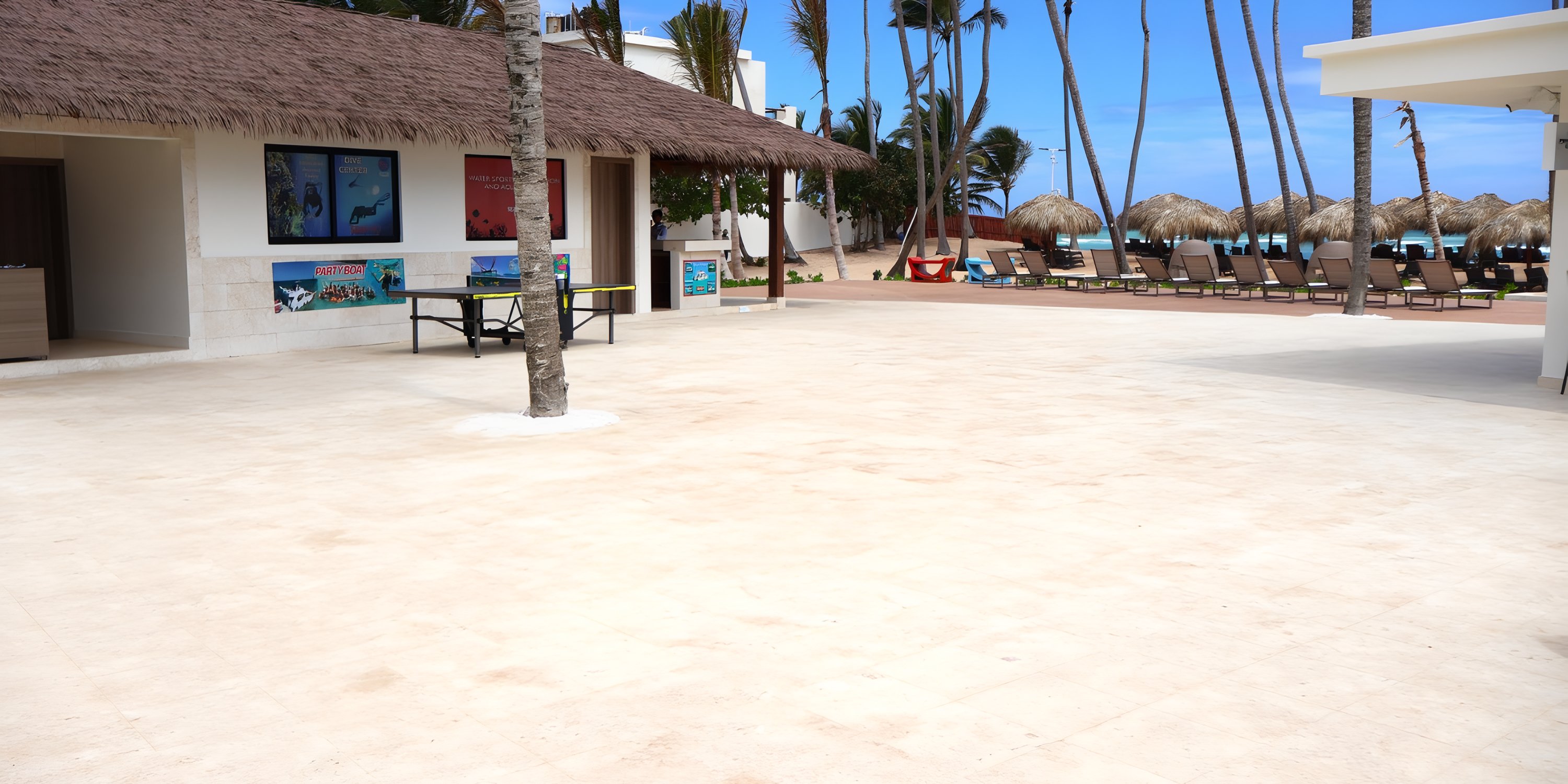 Scenic outdoor resort ideal for a destination wedding, with thatched-roof, palm trees, and beach loungers.