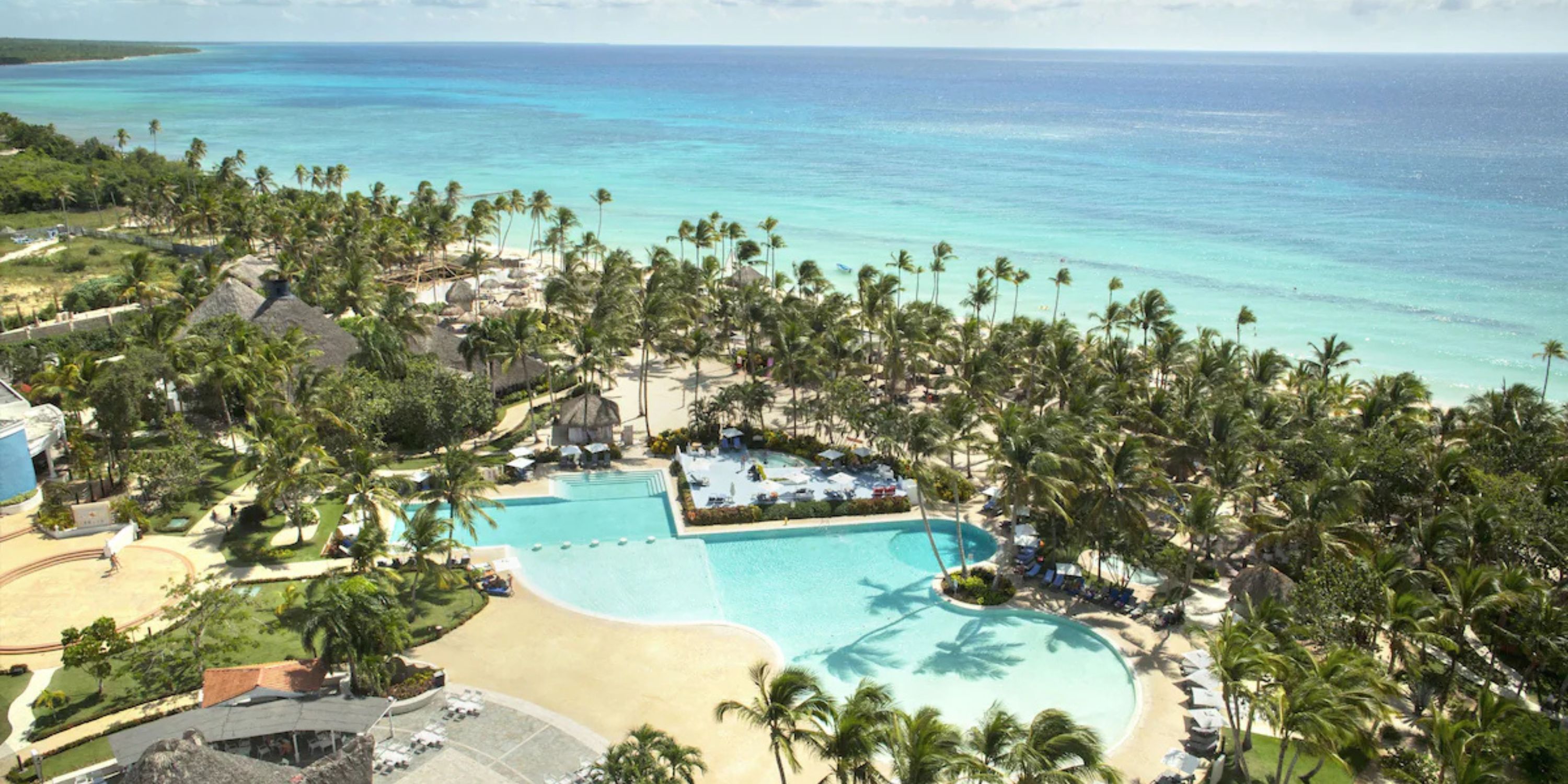 Aerial view of Catalonia Bayahibe, a beachfront resort with pools and palm trees&mdash;ideal for weddings.