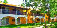 Catalonia Bayahibe: Ideal destination wedding spot with a two-story yellow building, arches, trees, and grass.