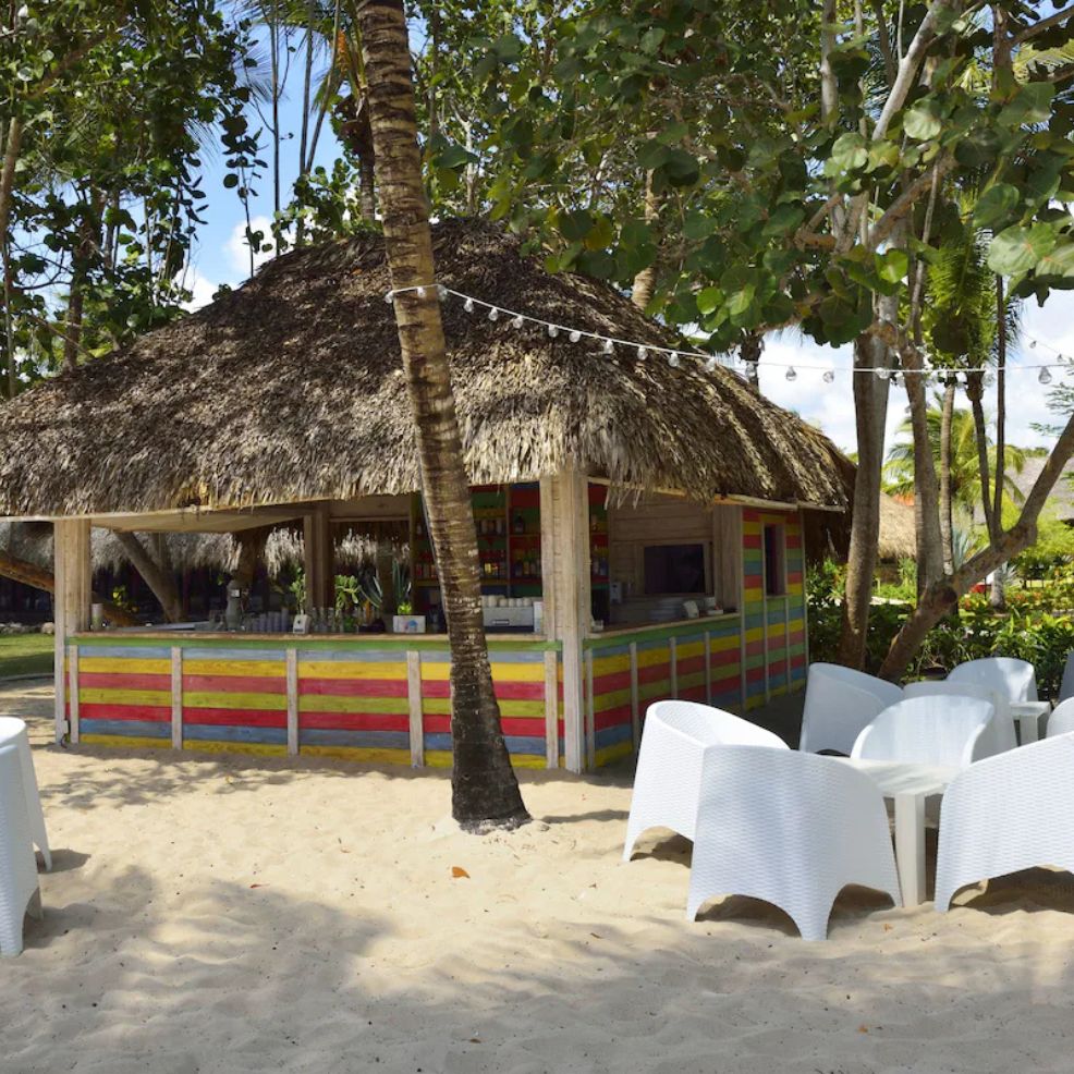 Beachside tiki bar with a thatched roof and colorful wood panels, perfect for a destination wedding.