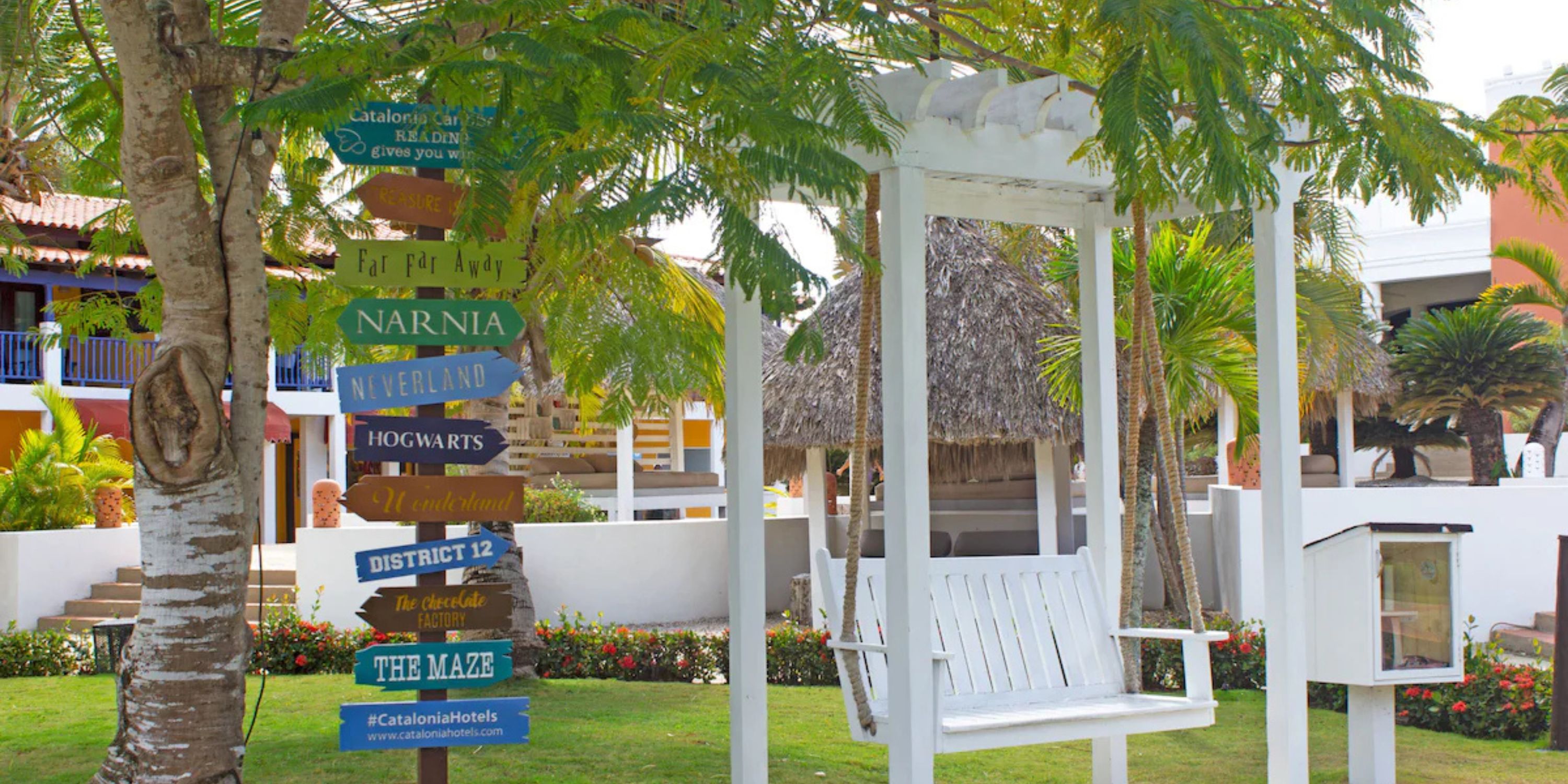 White swing near a tree with colorful signs in a garden, perfect for a destination wedding at Catalonia Bayahibe.
