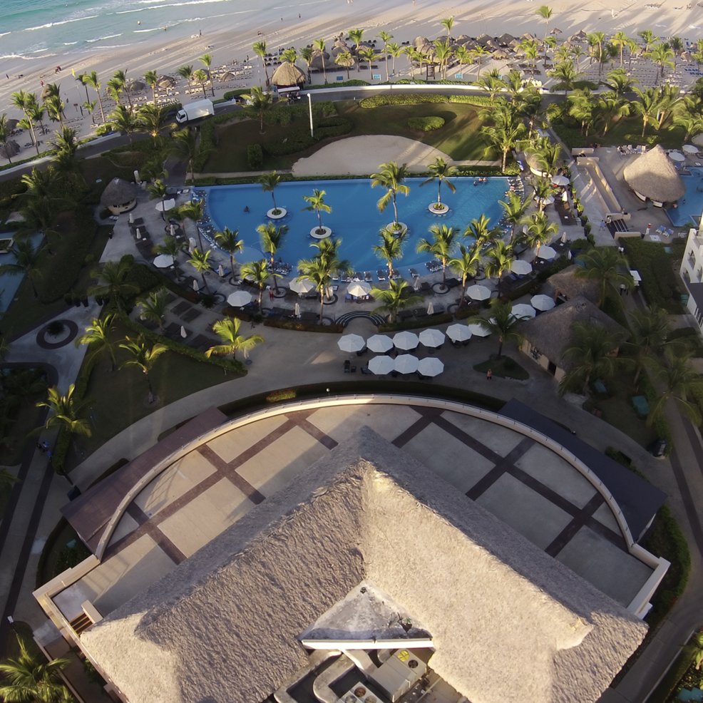 Aerial view of a resort pool area with palm trees, perfect for a destination wedding by the ocean.