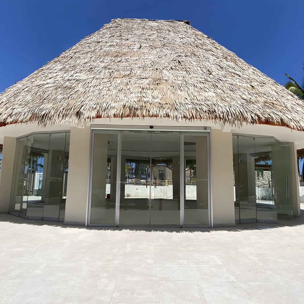 A charming venue with a thatched roof and glass doors, perfect for a destination wedding under clear skies.