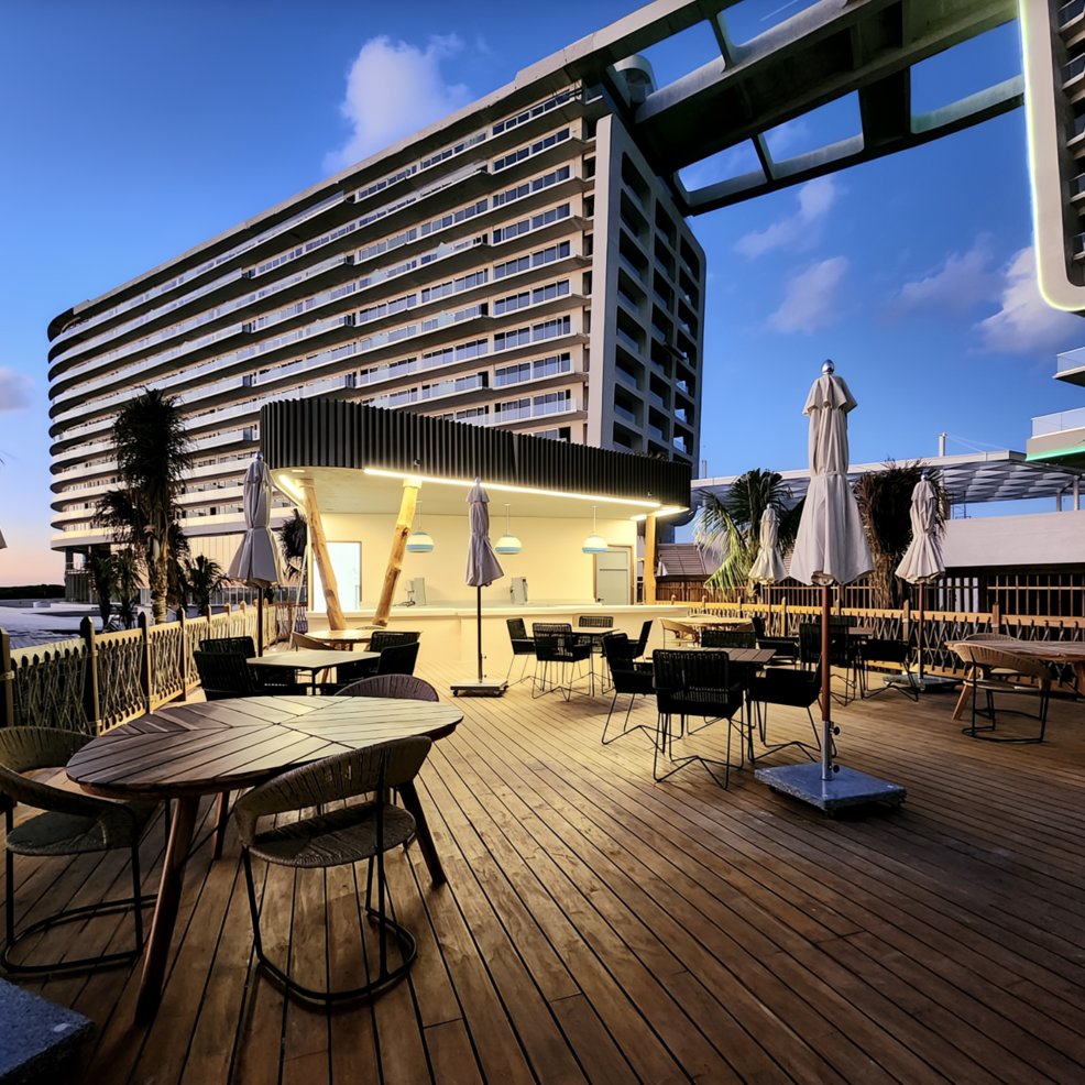 Wooden deck with outdoor seating, perfect for a destination wedding, modern hotel backdrop at sunset.