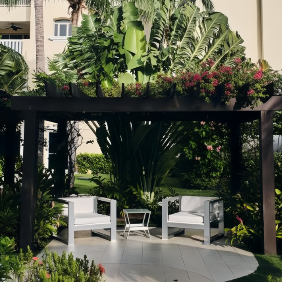 Two white chairs and a small table rest under a pergola, evoking a destination wedding setting amidst greenery.