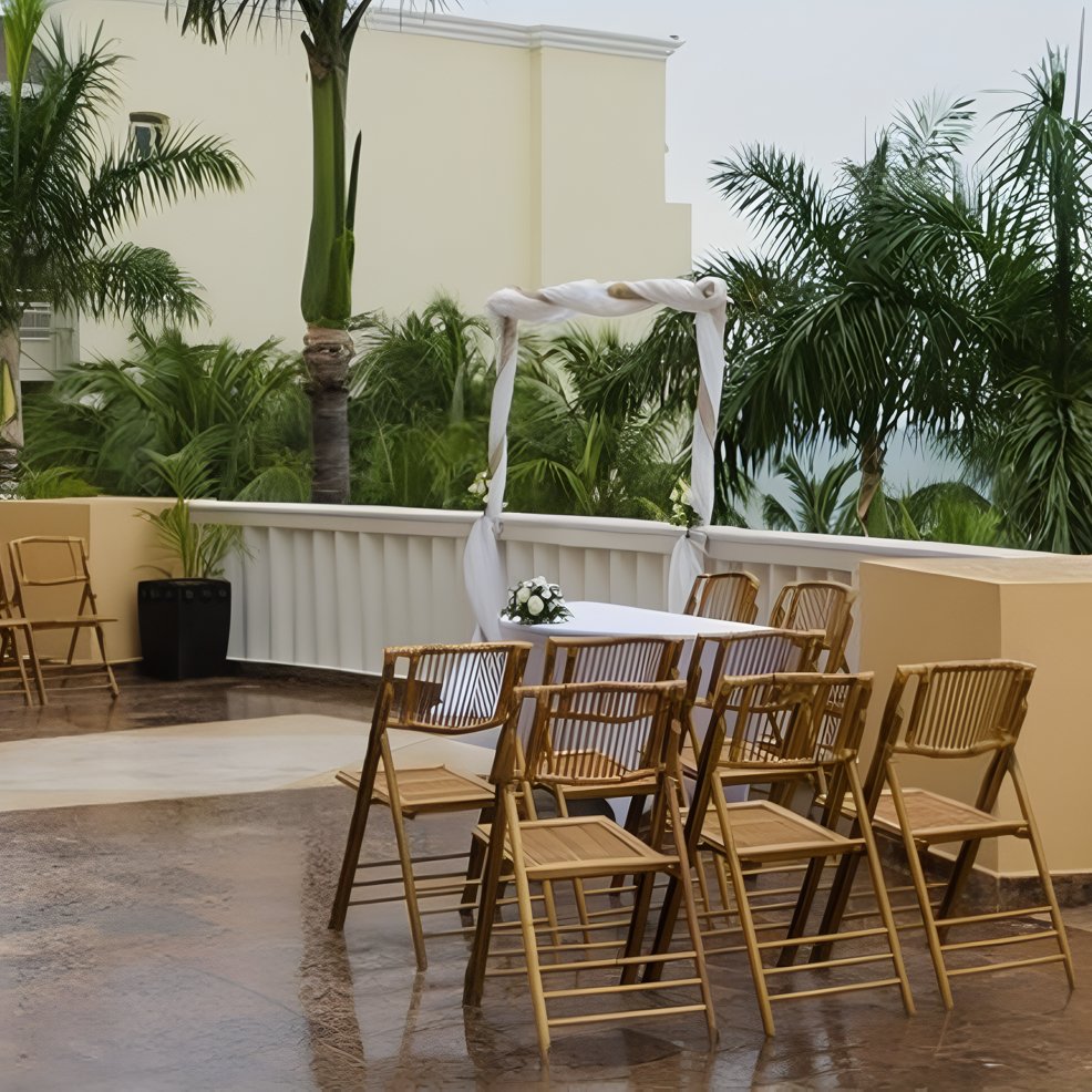 Rows of wooden chairs face a small table with flowers under an arch at an outdoor destination wedding.