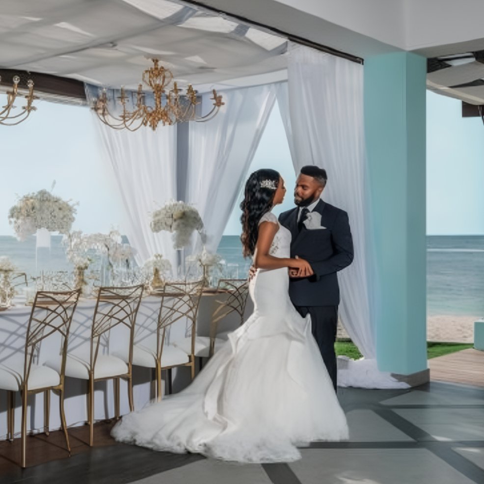 Bride and groom stand side by side at a beautifully set table during their destination wedding by the ocean.